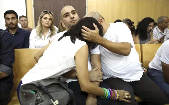  ??  ?? Elor Azaria, center, is embraced by his parents during a hearing at a military court in Tel Aviv on Sunday. (AP)