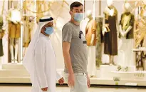  ?? AFP ?? Testing times: Shoppers wear masks in the Mall of Dubai amid lockdown easing in the emirate, above; a security guard screens a customer at a Riyadh mall, right; a health worker takes a sample at a drive-through testing center in Dubai, far right.