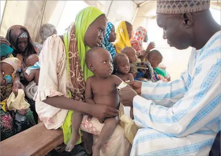  ?? Florian Plaucheur AFP/Getty Images ?? A HEALTH worker checks a child for malnutriti­on at a UNICEF clinic in Dikwa, Nigeria. President Trump’s budget blueprint sparked concerns that the U.S. was retreating from its historical support for internatio­nal aid to avert starvation and hunger...
