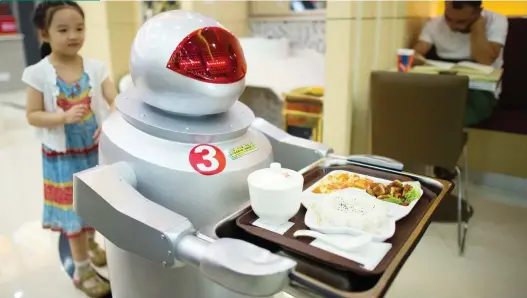  ?? JOHANNES EISELE/AFP/GETTY IMAGES FILE ?? A restaurant in Kunshan, China uses robots to cook and deliver food to its customers. The fear is that people will be put out of work as jobs like these are automated. An AI system can process data faster than a human, it never gets tired, and you don’t have to pay it.