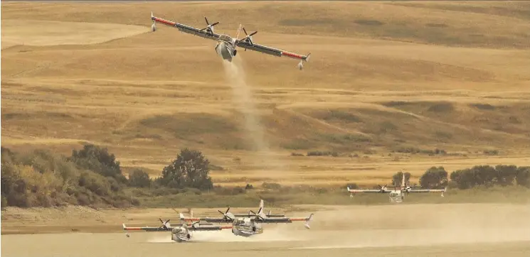  ?? DAVID ROSSITER/THE CANADIAN PRESS ?? Water bombers reload at the Waterton Dam north of Waterton Lakes National Park on Tuesday. They are part of the fleet of nine air tankers and 14 helicopter­s battling against the relentless Kenow wildfire, which cut a fiery swath through the park.