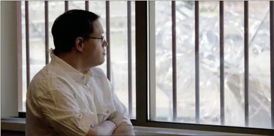  ?? JIM MONE — THE ASSOCIATED PRESS ?? Christophe­r Lee looks through a window secured by bars towards a barbed wire fence surroundin­g the building from a conference room at the Minnesota Sex Offender Program in St. Peter, Minn., on. Lee has been in the program since 2005, four days before...