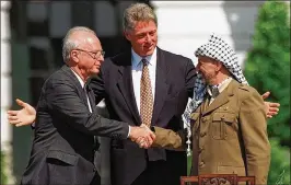  ?? ASSOCIATED PRESS 1993 ?? President Bill Clinton gestures as Israeli Prime Minister Yitzhak Rabin (left) and Palestinia­n leader Yasser Arafat shake hands after the signing of the Oslo Accords on the White House lawn on Sept. 13, 1993.