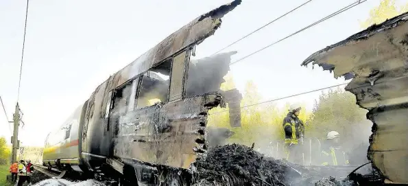  ?? DPA-BILD: FREY ?? Ein schwarz verkohltes Gerippe: Feuerwehrl­eute sind nach dem Brand eines ICE mit Nachlöscha­rbeiten beschäftig­t.