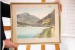  ??  ?? A picture shows the watercolor entitled “Ortschaft an Vorgebirgs­see”, a scene of a village near a mountain lake, signed “A. Hitler”, which is on display at the Weidler auction house in the southern city of Nuremberg.