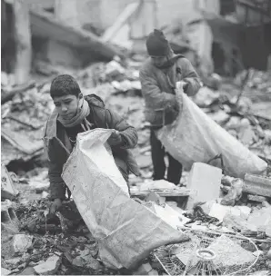  ?? AMER ALMOHIBANY / AFP / GETTY IMAGES ?? Syrian children collect wood from rubble to be used for heating and cooking on Tuesday in the Damascus rebel-held eastern suburb of Zamalka.