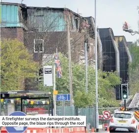  ??  ?? A firefighte­r surveys the damaged institute. Opposite page, the blaze rips through the roof