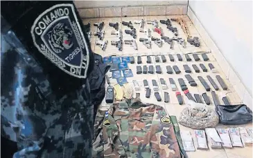  ??  ?? A HISTORY OF VIOLENCE: A police officer stands before an arsenal of weapons seized from a drug gang member last year.