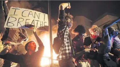  ?? JOHN MINCHILLO/AP ?? Protesters demonstrat­e outside a burning Minneapoli­s 3rd Police Precinct on Thursday. Protests over the death of George Floyd, a black man who died in police custody on Monday, broke out in Minneapoli­s for a third straight night.