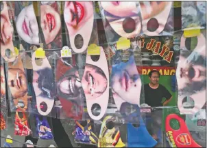  ?? (File photo/AP/Achmad Ibrahim) ?? A man is seen Thursday through a display of fun face masks for sale at a roadside stall in Jakarta, Indonesia. Indonesia has the highest numbers of coronaviru­s infections and fatalities in Southeast Asia.