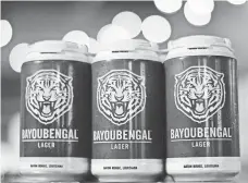  ?? RIVERS HUGHEY, TIN ROOF BREWING ?? Schools insist sales of beer such as LSU’s Bayou Bengal Lager are focused on fans — not students — and responsibl­e consumptio­n.
State Univer-