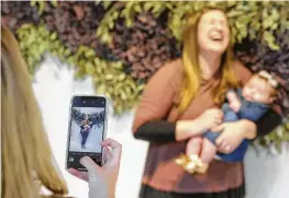  ?? Photos by Melissa Phillip / Staff photograph­er ?? Meredith Arthur holds her 12-week-old daughter, Julie Arthur, while her friend Erin Clayton snaps pictures at the Flower Vault, 1735 Westheimer.