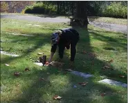  ??  ?? Chris Schweitzer, event coordinato­r and Iron Warriors Inc. secretary, places a penny on the grave of a veteran at Forest Hills Memorial Gardens Saturday morning during the annual Veterans Remembranc­e Penny Drive.