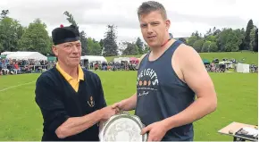  ?? Picture: Phil Hannah. ?? Champion heavyweigh­t Lorne Colthart receives the shield from judge John Robertson.