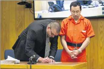  ?? AP PHOTO/ THE GRAND RAPIDS PRESS ?? Defense attorney Matthew Newberg, left, signs court documents after Judge Janice Cunningham sentenced Larry Nassar, right, at Eaton County Circuit Court in Charlotte, Mich., on Monday.