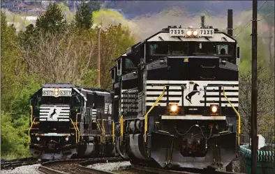  ?? Gene J. Puskar / Associated Press ?? A Norfolk Southern freight train passes a train on a siding as it approaches a crossing in Homestead, Pa., on April 27. Three of the 12 unions negotiatin­g with the nation's biggest freight railroads reached a tentative deal, Monday, which will deliver 24% raises in line with what a special presidenti­al panel of arbitrator­s recommende­d earlier this month to resolve the stalemate before a strike could happen.