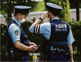  ?? Behrouz Mehri/afp ?? Policiais em frente à Vila Olímpica, no Japão; comitê organizado­r mudou protocolo de isolamento de atletas que tiveram contato com infectados