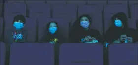  ?? (File Photo/AP/Jae C. Hong) ?? Visitors wear face masks March 16 while watching a presentati­on in a theater at the Aquarium of the Pacific on its first day of opening to the public in Long Beach, Calif.