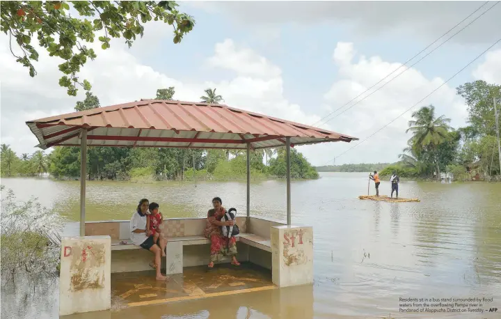  ?? — AFP ?? Residents sit in a bus stand surrounded by flood waters from the overflowin­g Pampa river in Pandanad of Alappuzha District on Tuesday.