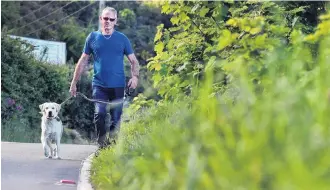  ?? PHOTO: PETER MCINTOSH ?? Needs a trim . . . Kevin Braid and his dog Free walk on an uncut grass verge in Aramoana Rd, near Deborah Bay.