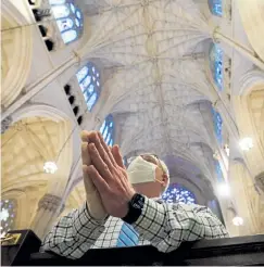  ?? Bryan R. Smith, AFP file photo/ Getty Images ?? A man wearing a face mask prays inside St. Patrick's Cathedral in New York.