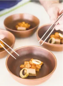  ??  ?? Left: Michael Warring works on preparing a dish of ocean trout with foie gras, hearts of palm, fennel pollen and popcorn jus. Right: Warring cooks a noodle dish with fairytale eggplant, guanciale, padron peppers and black truffle. Below: A dish of...