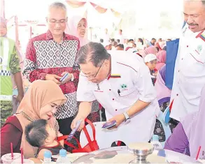  ??  ?? Dato’ Sri Ismail Sabri Yaakob (dua dari kanan) menyampaik­an sumbangan duit raya kepada salah seorang tetamu cilik Majlis Jamuan Hari Raya RISDA ESTATES.