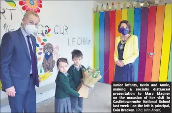  ?? (Pic: John Ahern) ?? Junior infants, Kevin and Annie, making a socially distanced presentati­on to Mary Magner on the occasion of her visit to Castletown­roche National School last week - on the left is principal, Eoin Bracken.