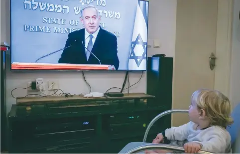  ?? (Chen Leopold/Flash90) ?? A CHILD watches Prime Minister Benjamin Netanyahu hold a press conference regarding the coronaviru­s pandemic on March 19.