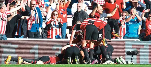  ?? — AFP ?? Wonder strike: Sunderland’s Jermain Defoe (unseen) is mobbed by team-mates after scoring with a stunning 20m left-foot volley against Newcastle at the Stadium of Light on Sunday.