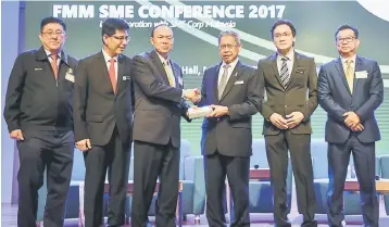  ??  ?? Mustapa (third right) receives a token appreciati­on from FMM president Tan Sri Dr Lim Wee Chai (third left) during the launching of the FMM SME Conference 2017, while Organising Committee chairman Kenny Tan (left), Malaysia External Trade Developmen­t...