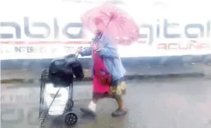  ?? ?? ▮ Sin importar si está lloviendo, ella cumple con su trabajo, que le da para mantenerse y mantener a su familia.