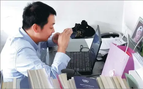  ?? LI LEI / CHINA DAILY ?? Cai Cong, project director of the Youren Foundation, uses an app on his cellphone and special computer software to work in his office in Beijing.