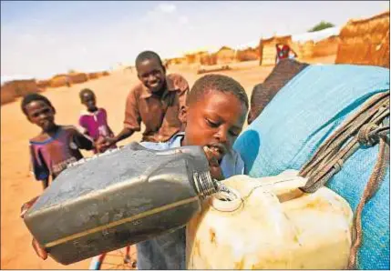  ?? AFP Photo / Ashraf Shazly ?? Unos niños llenan un bidón de agua en el campo de refugiados de Al-Nimir, en Darfur, Sudán del Sur