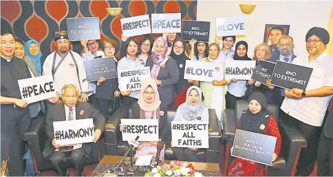  ?? — Photo by Muhammad Rais Sanusi ?? Fatimah (seated second left) together with (seated from left) Ngenang, Rosey, Zabariah and SWFC members show placards bearing motivation­al hashtags that call for unity across faiths.