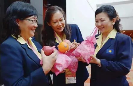  ??  ?? Fruity delights: Wanita delegates (from left) Ton Hoon Eng, Wong Foon Leng and Tey Lay Cheng admiring the gift of apples and oranges they received at the 37th Wanita MCA annual general meeting.