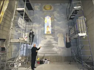  ??  ?? Le père Gil Florini devant l’imposant chantier de la fresque en cours de réalisatio­n, dans l’un des espaces libres de l’église Saint-Pierre d’Arène. L’église va recevoir de nouveaux saints…