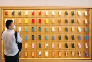  ?? REUTERS • FILE ?? A man stands in front of a wall of iPhones cases in the new Apple flagship store on its opening day following an outbreak of the coronaviru­s disease (COVID-19) in Beijing on July 17.