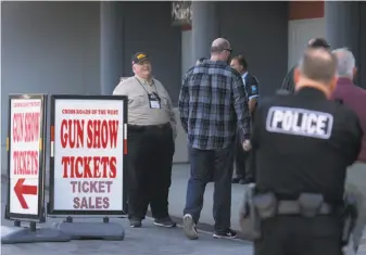  ?? Paul Chinn / The Chronicle ?? A man representi­ng the National Rifle Associatio­n (left) offers free admission to the Crossroads of the West gun show at the Cow Palace for people who join the NRA or those who renew.