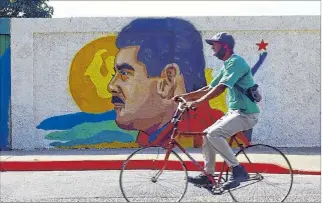  ?? EL PAÍS ?? País. Un hombre pasa junto a un mural del presidente venezolano, Nicolás Maduro.