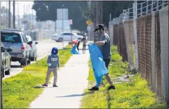  ??  ?? Kazuma and George Bicanec pick up trash. Torrance has a plan to improve the road this summer and make it a two-way thoroughfa­re again to make it more accessible to the public and discourage public drinking as well as illicit activities.
