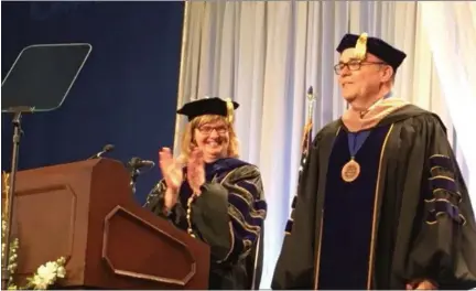  ?? KEVIN MARTIN — THE MORNING JOURNAL ?? LCCC President Marcia Ballinger (left) applauds as keynote speaker Michael J. Brown (right) prepares to receive his associate of arts degree at the 54th annual commenceme­nt ceremony on May 12 at the LCCC Ewing Activities Center Field House. Close to...