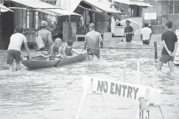  ??  ?? File photo shows people wading through a flooded street in the town of Baao in Camarines Sur province as storm swept through the central Philippine islands. — AFP photo