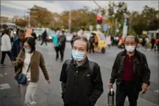  ?? Nicolas AsfouriI/AFP via Getty Images ?? People wearing face masks as a preventive measure against COVID-19 commute during rush hour Tuesday on a street outside of a shopping mall complex in Beijing.