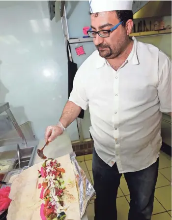  ?? RICK WOOD / MILWAUKEE JOURNAL SENTINEL ?? Chef Mohammad Alayna prepares a falafel sandwich at Holyland Restaurant, inside Holyland Grocery at 2755 W. Ramsey Ave., on the large flatbread called shrak. Holyland also has excellent beef-lamb and chicken shawarma.