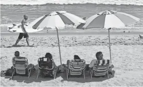  ?? TIM SHORTT/USA TODAY NETWORK ?? Surfers and beachgoers soak in the sun at Hightower Beach Park in Satellite Beach. The surge of the delta variant of the coronaviru­s has put Florida in the news for a sharp increase in cases and hospitaliz­ations, scaring away some would-be tourists.