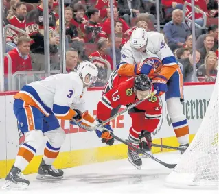  ?? ARMANDO L. SANCHEZ/CHICAGO TRIBUNE ?? Blackhawks left wing Henrik Borgström is struck in the face by the stick of New York Islanders defenseman Scott Mayfield, right, during the first period of Tuesday night’s game.