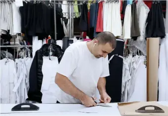  ??  ?? STARTING FROM SCRATCH: Ahmad Zaki cuts fabric for a coat at the M. Miller store.