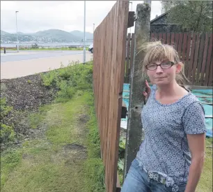  ?? F33 Monika Caol garden 1IF ?? Monika Niezbecka at the fence which separates her back garden and the controvers­ial grass strip in Glenkingie Street, Caol.