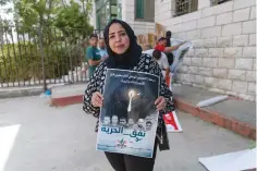  ?? The Associated Press ?? ■ Sahar Abdullah carries a poster with pictures of the six Palestinia­n prisoners who escaped from an Israeli jail that says “the freedom tunnel,” during a Sept. 14 protest in the West Bank city of Ramallah.